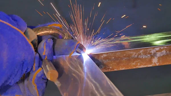 Metal kaynak kıvılcım ve duman ile. İşçi kaynak metal koruyucu maske ile. Kaynakçı metal parçalar katılır. Bir yarı otomatik kaynak kullanan işlem. Kaynak çelik. Fabrikada sanayi işçisi