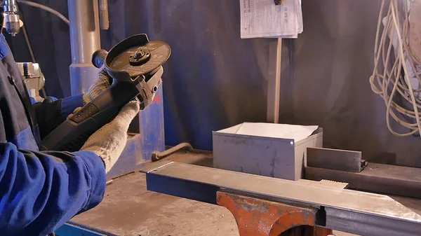 Zanaatkar atölyede disk öğütücüyle metal testeresi kesiyor. Metal testereyle kesiliyor. Metal testeresi üreten bir işçi. Ağır çekimde endüstri