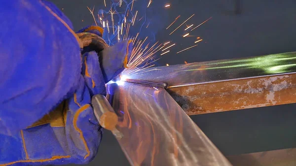 Metal kaynak kıvılcım ve duman ile. İşçi kaynak metal koruyucu maske ile. Kaynakçı metal parçalar katılır. Bir yarı otomatik kaynak kullanan işlem. Kaynak çelik. Fabrikada sanayi işçisi