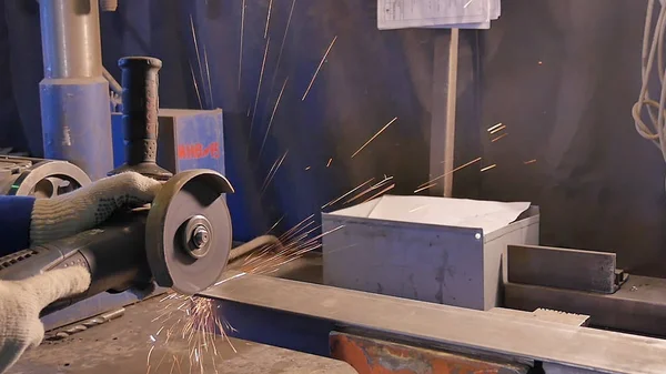 Ремесленник пилит металл с дисковым шлифовальным станком в мастерской. Металлическое пиление крупным планом. Работник по производству пильного металла. Промышленность в замедленной съемке — стоковое фото