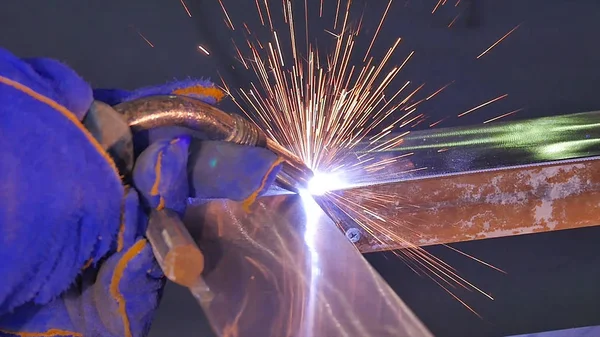 Metal kaynak kıvılcım ve duman ile. İşçi kaynak metal koruyucu maske ile. Kaynakçı metal parçalar katılır. Bir yarı otomatik kaynak kullanan işlem. Kaynak çelik. Fabrikada sanayi işçisi