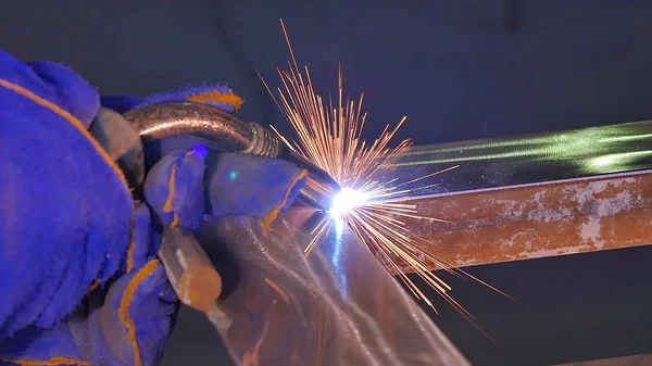 Metal kaynak kıvılcım ve duman ile. İşçi kaynak metal koruyucu maske ile. Kaynakçı metal parçalar katılır. Bir yarı otomatik kaynak kullanan işlem. Kaynak çelik. Fabrikada sanayi işçisi
