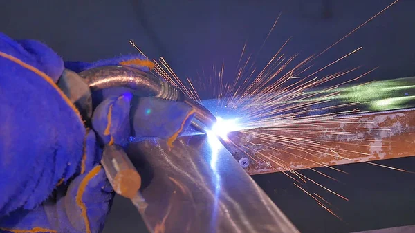 Metal kaynak kıvılcım ve duman ile. İşçi kaynak metal koruyucu maske ile. Kaynakçı metal parçalar katılır. Bir yarı otomatik kaynak kullanan işlem. Kaynak çelik. Fabrikada sanayi işçisi