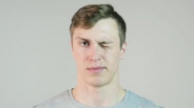 Göz kırpıyor, beyaz arka plan üzerinde izole genç adam. Mutlu bir adam bir göz kırpıyor yakın çekim. Göz kırpıyor ve having fun yavaş beyaz arka plan üzerinde neşeli neşeli genç adam