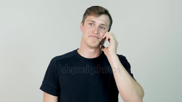 Portrait of a casual young man speaking on the phone. Young man is standing with mobile phone and is talking with his girlfriend — Stock Video