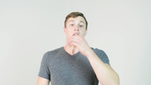 Junger Mann niest auf weißem Hintergrund. Porträt eines niesenden Menschen. junger Mann hält ein Taschentuch und niest auf weißem Hintergrund — Stockvideo