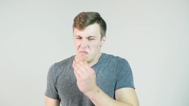 Junger Mann niest auf weißem Hintergrund. Porträt eines niesenden Menschen. junger Mann hält ein Taschentuch und niest auf weißem Hintergrund — Stockvideo