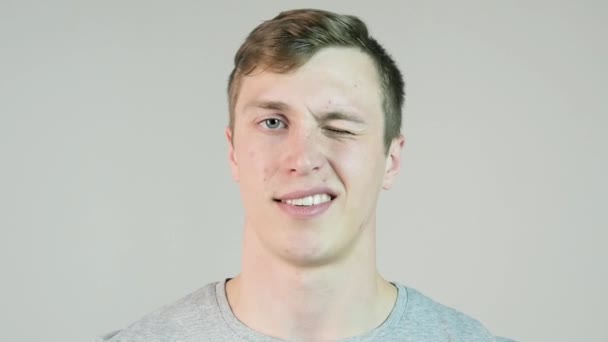 Young man winking, isolated on white background. Close up of a happy man winking an eye. Cheerful joyful young man winking and having fun over white background in slow motion — Stock Video