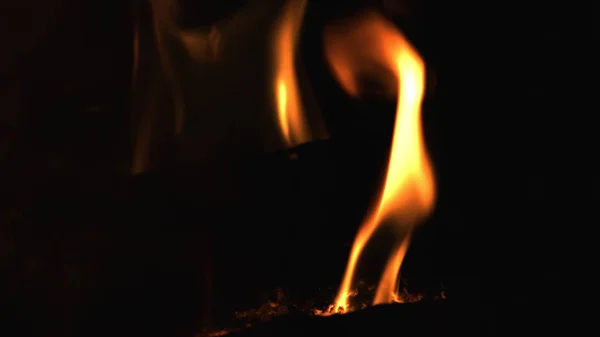 Nahaufnahme von brennendem rotem Feuerholz auf schwarzem Hintergrund. Brennholz im Kamin verbrennen. — Stockfoto