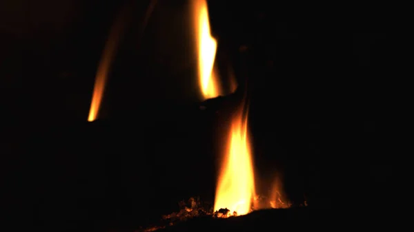 Nahaufnahme von brennendem rotem Feuerholz auf schwarzem Hintergrund. Brennholz im Kamin verbrennen. — Stockfoto