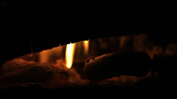 制作和烹调过的热狗香肠打开篝火。烧烤食物在火焰上木制的分支-的篝火棍子矛在夜的性质. — 图库照片
