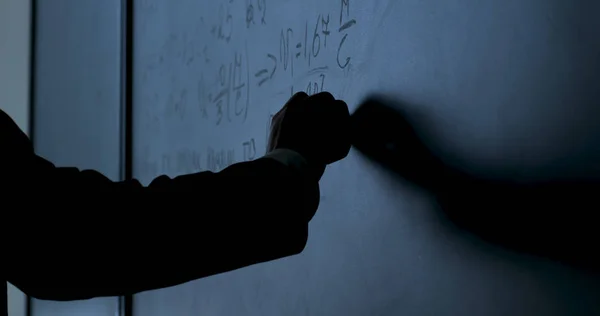 Ученый пишет формулы на доске. Рука с мелом написала формулы физики на черной доске крупным планом — стоковое фото
