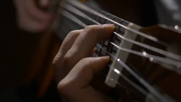 Närbild av gitarristen hand spelar akustisk gitarr. Nära upp skott av en man med fingrarna på banden av en gitarr som spelar — Stockfoto