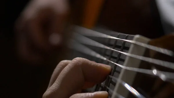 Close up da mão do guitarrista tocando guitarra acústica. Close up tiro de um homem com os dedos nos trastes de uma guitarra tocando — Fotografia de Stock