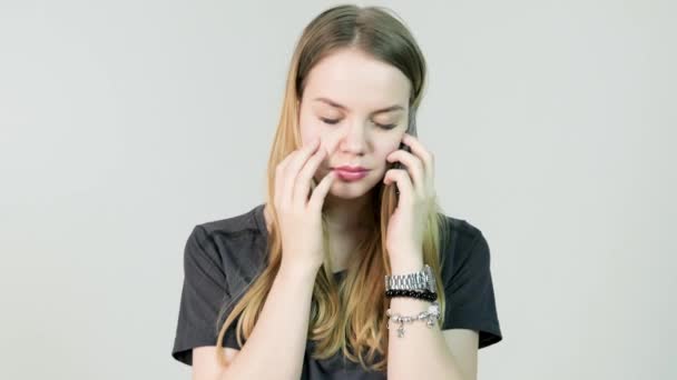 Junge Frau wütend, weinen, verwirrt, traurig, nervös, aufgebracht, Stress und Denken mit ihrem Mobiltelefon, schönes junges Mädchen, isolierter weißer Hintergrund — Stockvideo