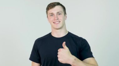 Kameraya bakarak ve yukarı hareketi gösterilen beyaz arka plan üzerinde siyah t-shirt ayakta giyinmiş genç çekici adam