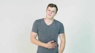 Beyaz arka plan üzerinde bir karın ağrısı olan bir genç adam. Genç adam mide tutar, acıyor