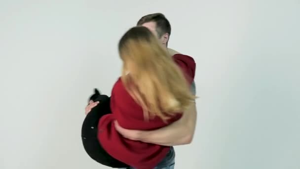 Парень заводит девушку. Молодой человек поворачивает девушку на руках на белом фоне, замедленная съемка — стоковое видео