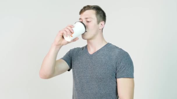 Jongeman koffie drinken uit disposable paper cup op witte achtergrond — Stockvideo