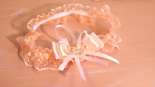 Krásné nevěsty růžové svatební podvazek leží na posteli. Svatební krajkový podvazek jako srdce čeká nevěsty. Selektivní fokus. — Stock fotografie