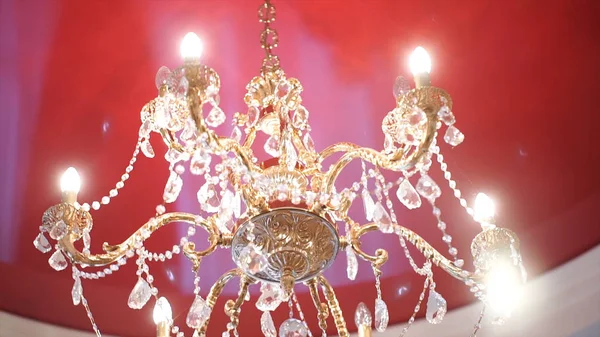 Lustre en cristal de luxe sur le plafond rouge.Beau lustre en cristal à la lumière ambiante — Photo