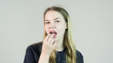 Genç sevimli gülümseyen kadın ağzına sakız beyaz zemin üzerine koyar