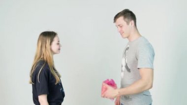 Beyaz bir arka plan üzerinde hediye ile mutlu genç çift. Mutlu adam kız arkadaşına bir hediye vermek