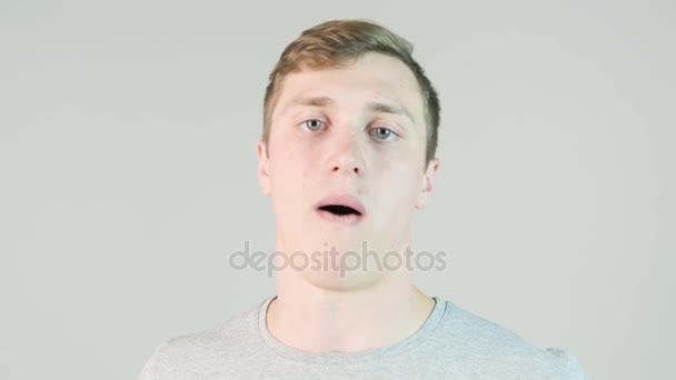 Jonge man het eten van een stukje van snoep op witte achtergrond — Stockvideo