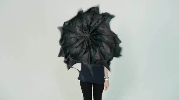 Jovem mulher abre guarda-chuva preto no fundo branco, câmera lenta — Vídeo de Stock