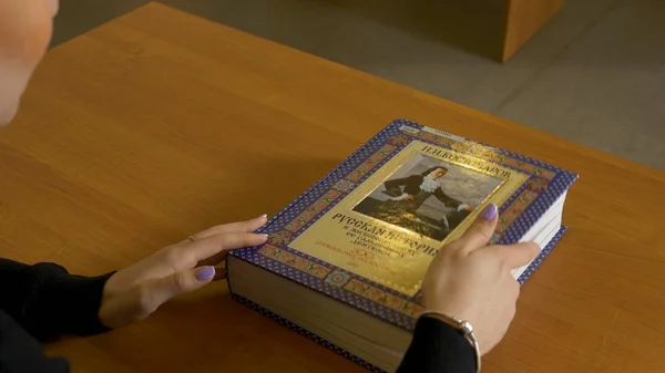 Kvinna sitter läsning på bordet. Kvinna stänger boken efter behandlingen — Stockfoto