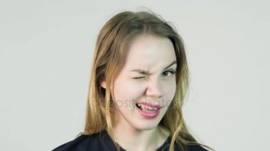 Kız winks üzerinde beyaz bacvkground. Gülümsemek gülümseyen ve göz kırpıyor mutlu bir genç kadın portresi. Çiller, dalgalı sağlıklı saçlar ile mükemmel cilt. Beyaz duvar izole.