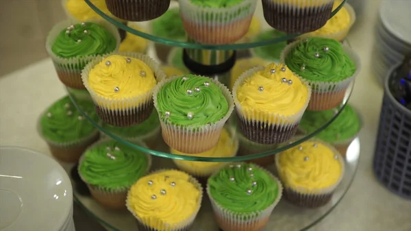 Cupcakes. Bolos de chocolate incríveis e cupcakes. Bolo de caramelo de chocolate com nozes e xarope de caramelo. Bolinhos verdes e amarelos. Belos cupcakes com cremes coloridos. Foco seletivo. Bokeh... — Fotografia de Stock