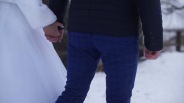 Dışında yürüme genç yeni evliler. Gelin ve damat birlikte kış veya yaz ve el ele parkta yürümek. mutlu gelin çift çalılar kiraz arasında parkta yürüyüş. Gelin ve damat