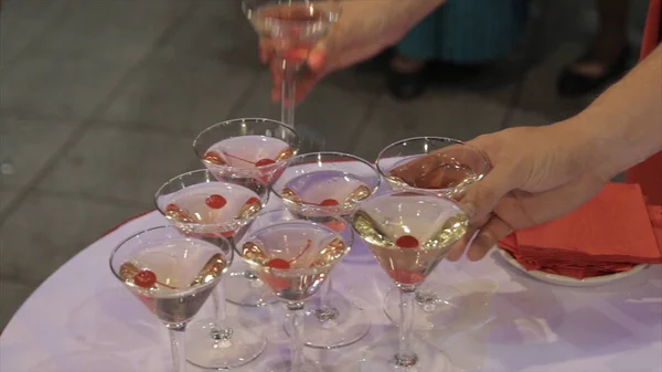 Människor tar från tabellen ett glas Martini och whiskey. Champagne i glas med färska körsbär på bordet och partiets bakgrund. Top View glasögon med olika alkohol drycker på ett bord på bröllop — Stockfoto