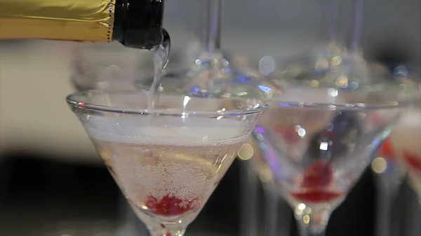Hälla i två glas från en flaska champagne. Två champagneglas på oskärpa — Stockfoto