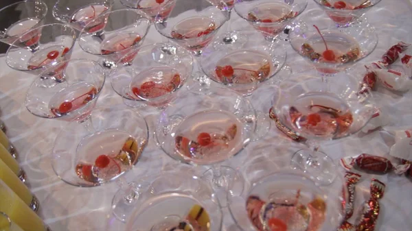 Champagne i glas med färska körsbär på bordet och partiets bakgrund. Top View glasögon med olika alkohol drycker på ett bord på bröllop. Pyramid av röd blå Champagne Martini glas vid evenemang — Stockfoto