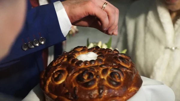 Pão e salto no casamento. O noivo polvilhe o pão com sal. Um símbolo da vida casada feliz e longa de noiva e noivo. Tradição do casamento russo. Esposa e noivo comer pão com sauld em — Fotografia de Stock