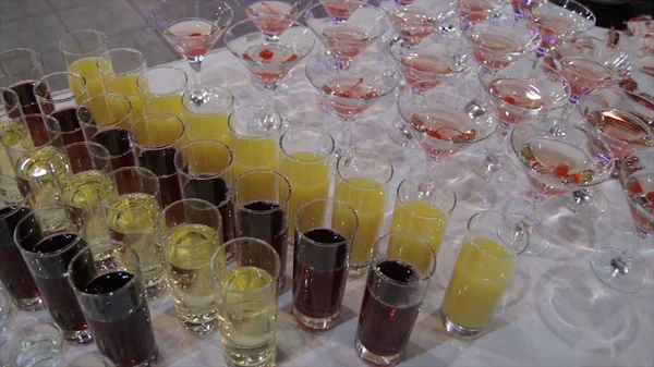 Champagne i glas med färska körsbär på bordet och partiets bakgrund. Top View glasögon med olika alkohol drycker på ett bord på bröllop. Pyramid av röd blå Champagne Martini glas vid evenemang — Stockfoto