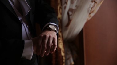 Damat kravat üzerinde takım elbise düğün elele geziyor. yakın bir el adamın giyer beyaz gömlek ve kol düğmesi nasıl. Siyah kravat beyaz forması sabitleme iş adamı. Damat Düğün günü sabitleme üzerinde kravat, vintage