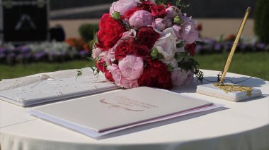 Menekşe ve mor çiçekler ile yeni evliler için dekorasyon düğün Arch kayıt tablosu ile. Kayıt defteri pembe çiçeklerle süslenmiş beyaz masa üzerinde duran güneş ışığı yanar.