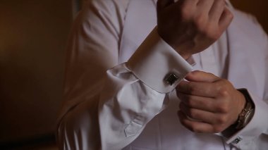 Damat kravat üzerinde takım elbise düğün elele geziyor. yakın bir el adamın giyer beyaz gömlek ve kol düğmesi nasıl. Siyah kravat beyaz forması sabitleme iş adamı. Damat Düğün günü sabitleme üzerinde kravat, vintage
