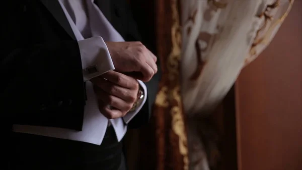 Groom is holding hands on the tie, wedding suit. close up of a hand man how wears white shirt and cufflink. Business man fixing black tie on white shirt. Groom on wedding day fixing tie, vintage