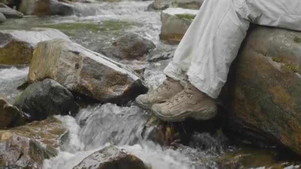 Водонепроникні трекінгові черевики на скелястому гірському потоці. Концепція високоякісного пішохідного обладнання — стокове відео