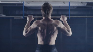 Plaka bar ile spor salonunda egzersiz güçlü adam. Yukarı, omuz ve kolları üzerinde egzersiz çeker. Arkadan Görünüm. Üzerinde kafa tutun. Yüksel egzersiz yapan kaslı erkek arkadan görünüm