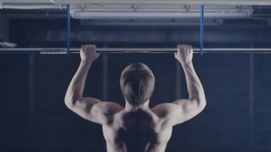 Plaka bar ile spor salonunda egzersiz güçlü adam. Yukarı, omuz ve kolları üzerinde egzersiz çeker. Arkadan Görünüm. Üzerinde kafa tutun. Yüksel egzersiz yapan kaslı erkek arkadan görünüm