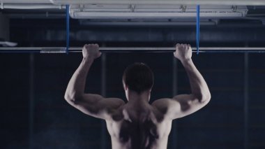 Plaka bar ile spor salonunda egzersiz güçlü adam. Yukarı, omuz ve kolları üzerinde egzersiz çeker. Arkadan Görünüm. Üzerinde kafa tutun. Yüksel egzersiz yapan kaslı erkek arkadan görünüm