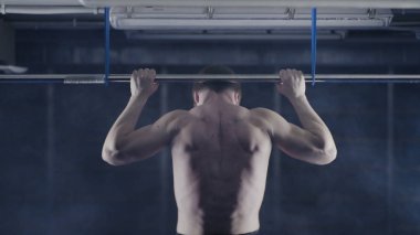 Plaka bar ile spor salonunda egzersiz güçlü adam. Yukarı, omuz ve kolları üzerinde egzersiz çeker. Arkadan Görünüm. Üzerinde kafa tutun. Yüksel egzersiz yapan kaslı erkek arkadan görünüm