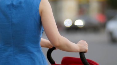 Genç anne ile bebek arabası sokak arkadan görünüm, yürüme kapatın. Bebek annesiyle sokakta yürüyor