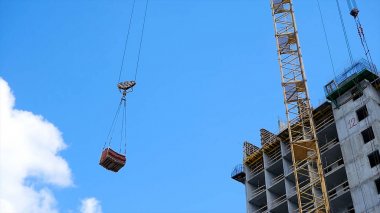 Vinç ve bina inşaat alanında mavi gökyüzü karşı. ağır yük inşaat yapım aşamasında tuğla vinç kanca asılı