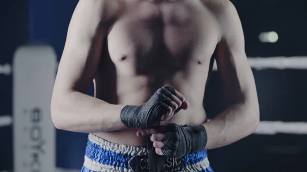 Primer plano de un luchador de artes marciales mixtas envolviendo sus manos antes de una pelea. Boxer envuelve su mano con un vendaje rojo antes del figh —  Fotos de Stock